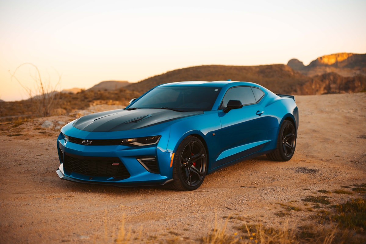 Blue Chevrolet Camaro in the desert at sunset